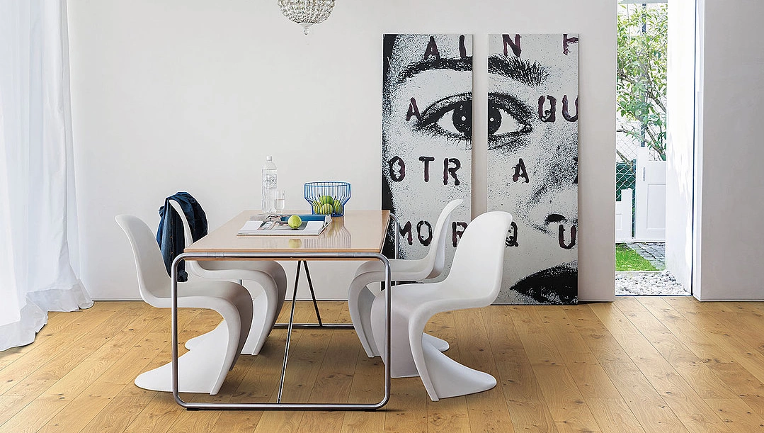 Ein heller Eichen Parkettboden verlegt in einem Esszimmer mit weißen Stühlen und sicht auf den Garten. Im Hintergrund des Bildes steht ein 2 geteiltes Bild. Ein heller Eichen Parkettboden verlegt in einem Esszimmer mit weißen Stühlen und sicht auf den Garten. Im Hintergrund des Bildes steht ein 2 geteiltes Bild.